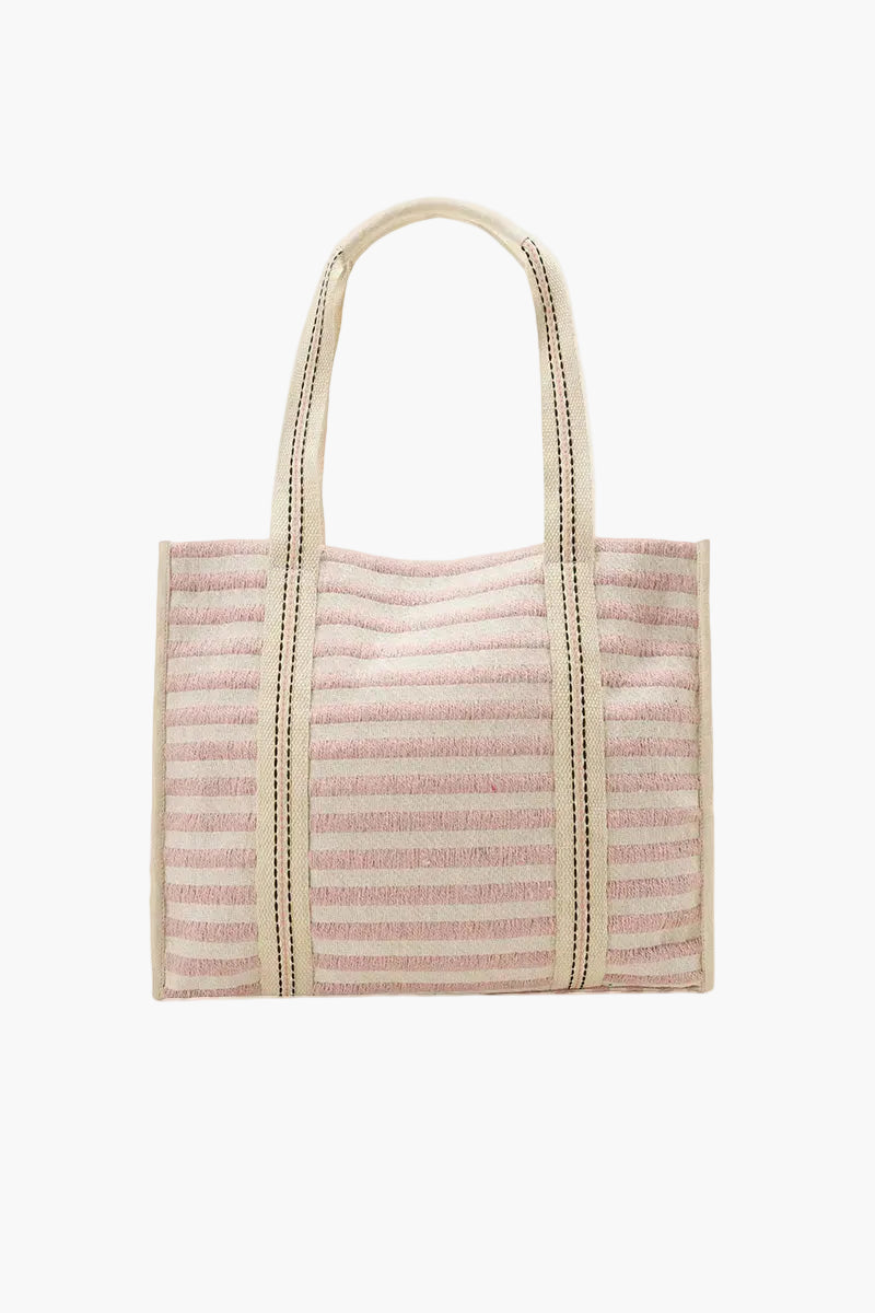 Pink woven tote bag with beige handle on a white background