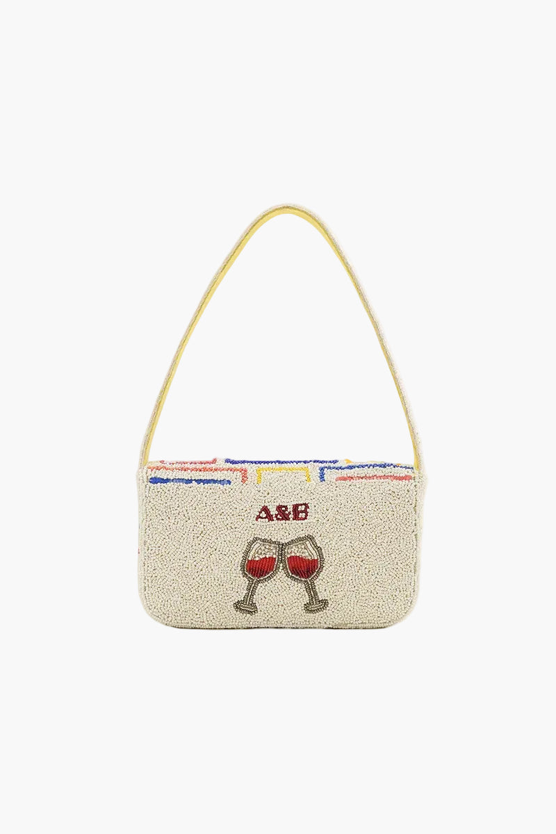 Beige handbag with red wine glass design and initials on a white background