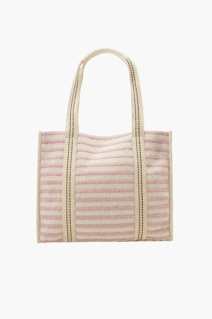 Pink woven tote bag with beige handle on a white background