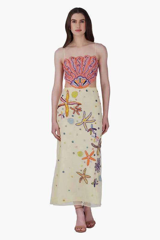 Woman wearing a dress with colorful shell and starfish patterns on a white background