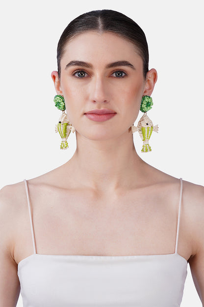 Woman wearing green and gold earrings against a white background
