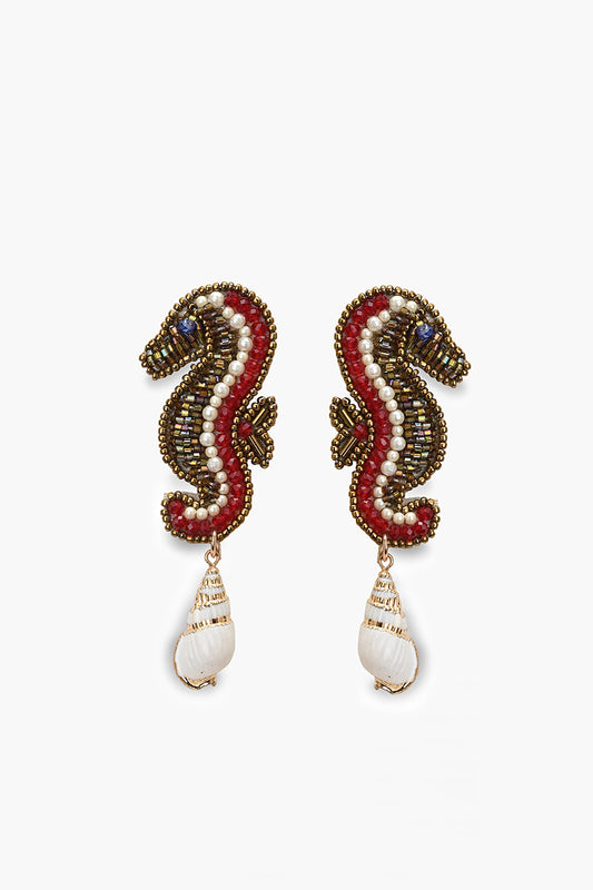 Pair of seahorse-shaped earrings with red and gold details on a white background
